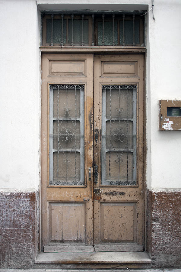 Photo 02639: Worn, yellow, panelled double door with grated top window
