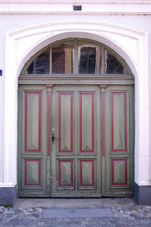 Photo 08764: Worn, panelled, green and red door with sidepieces and large fan light.