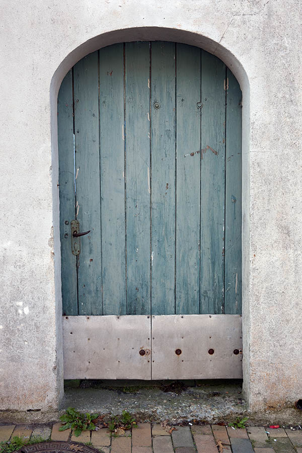 Photo 09446: Formed, teal door made of planks leading to a garden