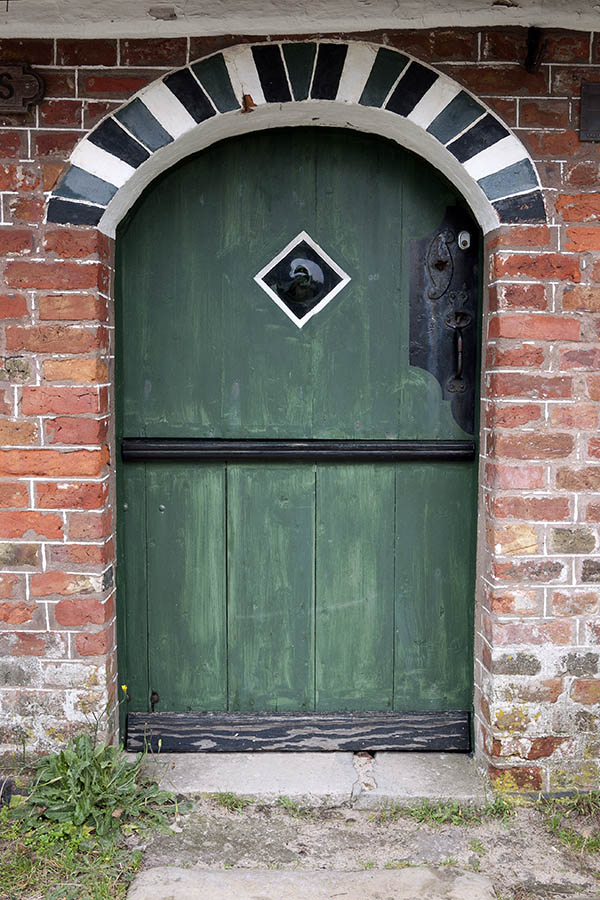 Photo 09784: Worn, green, black and white half-door made of planks with a diamond-shaped door light