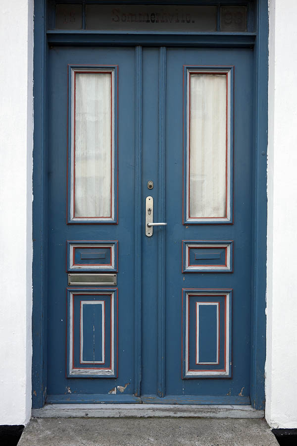 Photo 10691: Worn, panelled, blue, red and white double door with top window and door lights