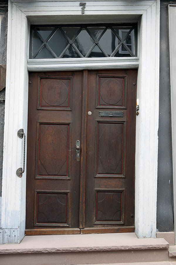 Photo 11908: Very lopsided, oiled and red double door with a grey top window and a white pilaster
