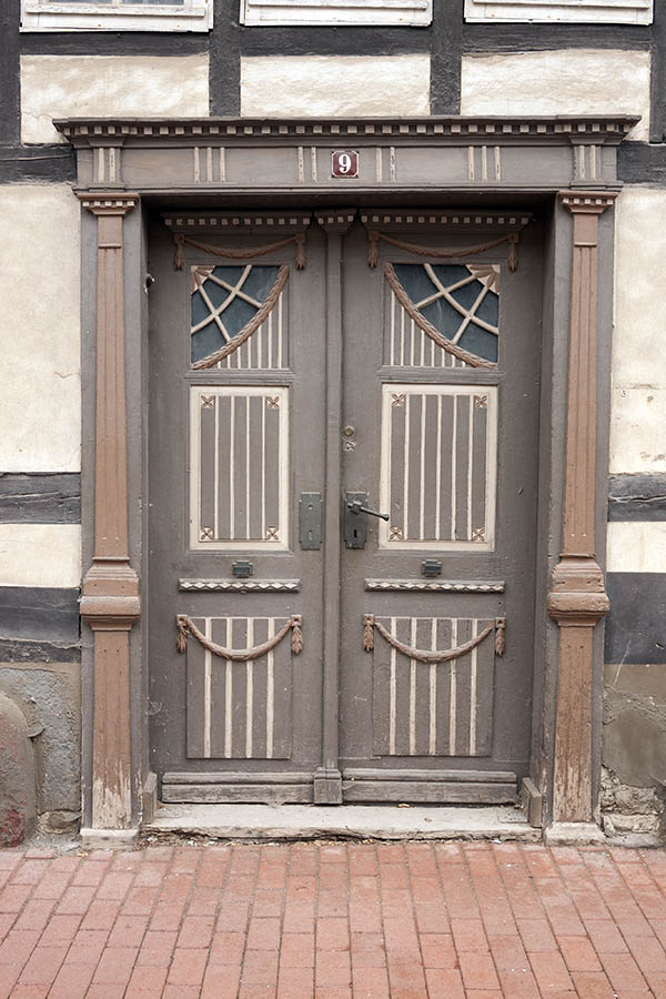 Photo 12378: Worn, carved, panelled, brown and light yellow double door with a lopsided pilaster and formed door 