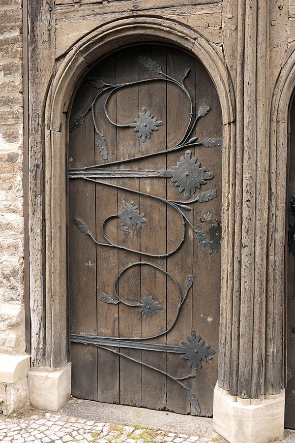 Photo 12712: Worn, formed, brown door made of planks with decoration of black iron