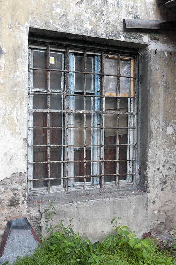 Photo 12943: Worn, unpainted, barred window with three frames and six panes