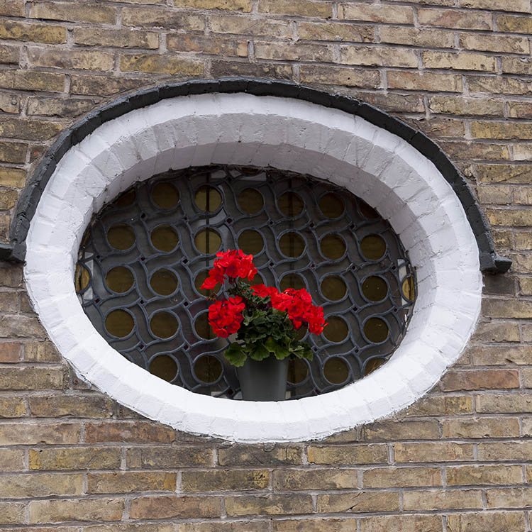 Photo 15668: Formed, oval, black window with many pieces of yellow and clear glass