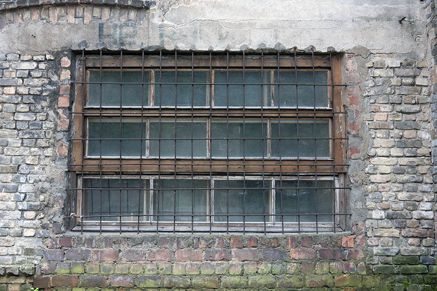 Photo 19150: Worn, barred, orange and brown window with three frames and 12 panes