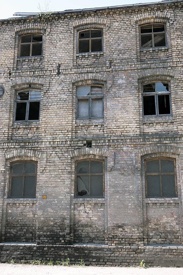 Photo 19606: Worn facade of yellow bricks with nine formed, decayed windows with four panes each