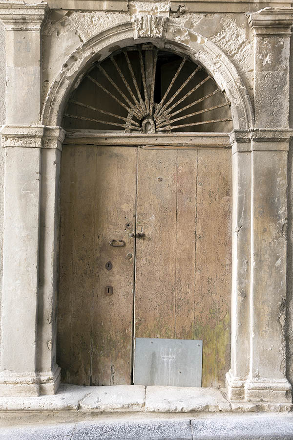 Photo 24409: Lopsided, worn, unpainted, brown double door of boards with latticed fan light