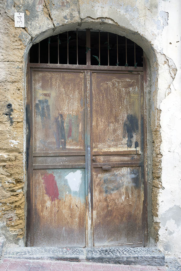 Photo 24485: Lopsided, brown and rusty gate with barred top window