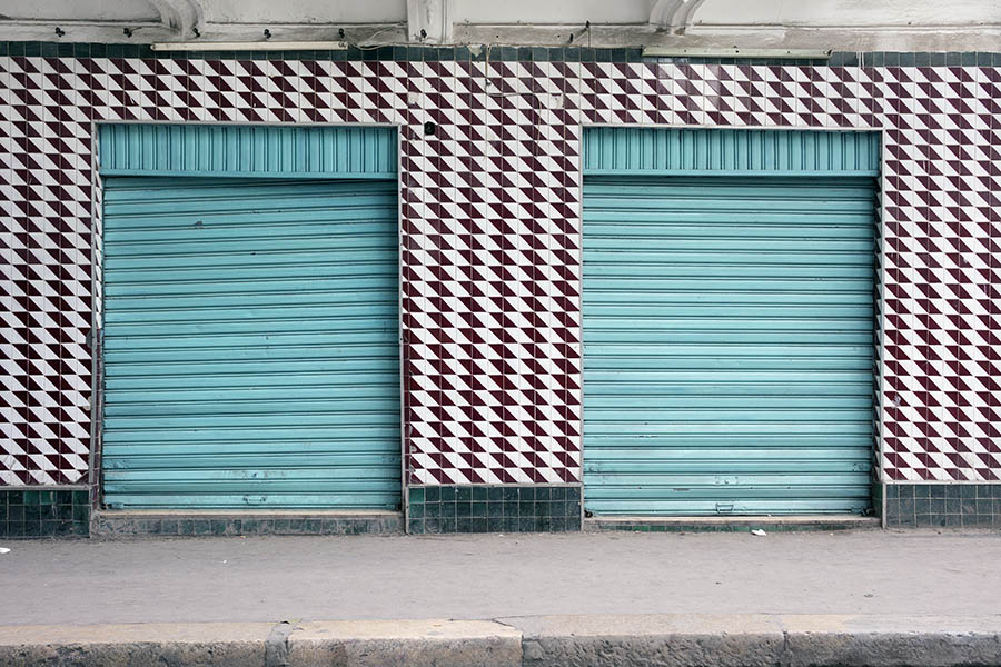 Photo 24546: Facade with brown and white tiles and two shop doors covered by turquoise security shutters