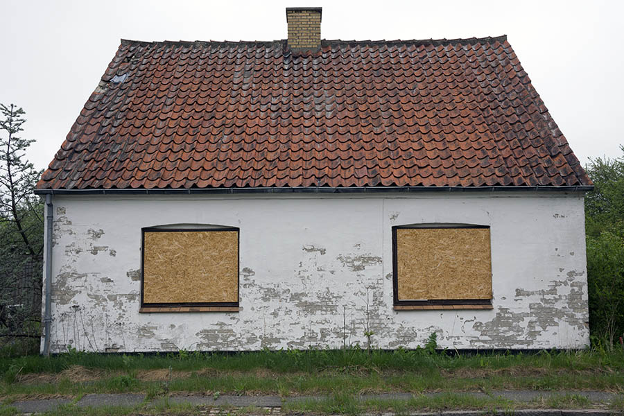 Photo 25138: Facade of worn, white house with blinded windows, ready for demolition