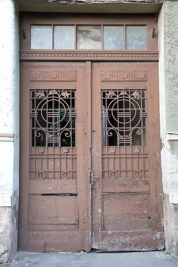 Photo 25618: Worn, panelled, carved, brown gate with latticed door lights and top window