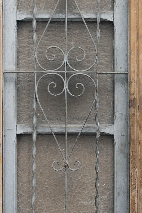 Photo 02639: Worn, yellow, panelled double door with grated top window