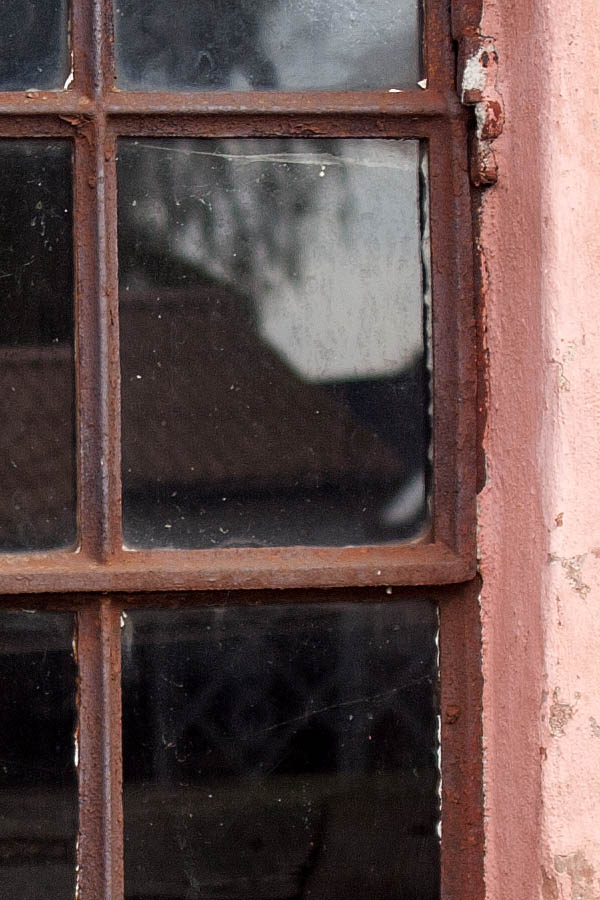 Photo 07739: Formed, rusty, brown metal stable window