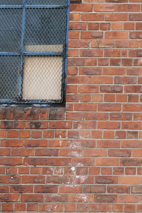 Photo 11502: Facade with red brickwork and seven worn, blue window