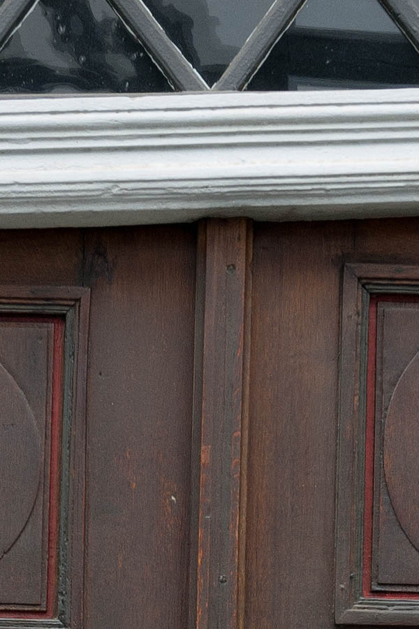 Photo 11908: Very lopsided, oiled and red double door with a grey top window and a white pilaster