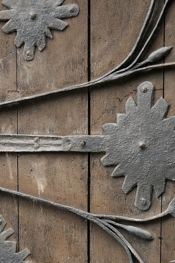 Photo 12712: Worn, formed, brown door made of planks with decoration of black iron