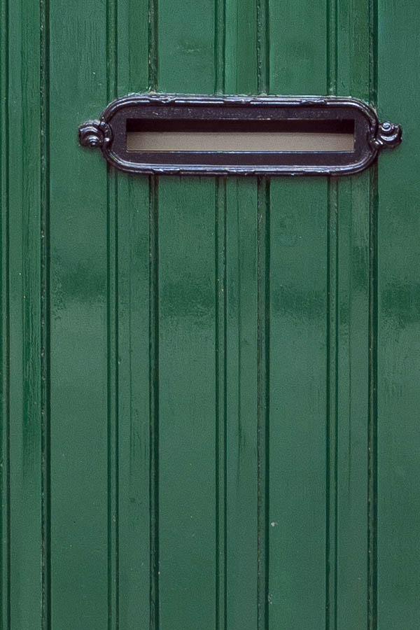 Photo 15912: Formed, green door made of planks with a formed, barred door light