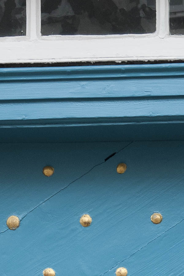 Photo 16418: Turquoise door made of planks with many nails with black and white top window