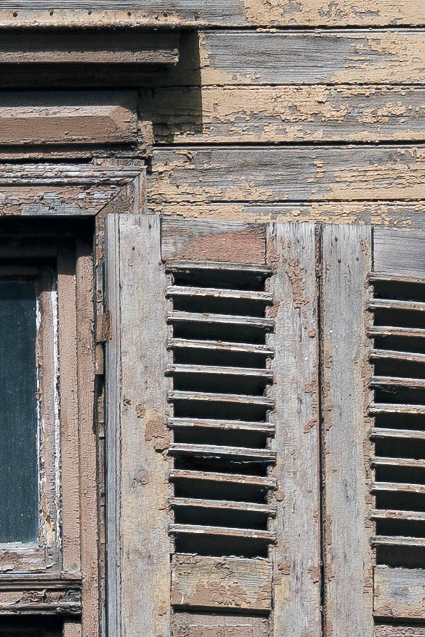 Photo 19804: Worn, light brown window with four frames, six panes and decayed shutters