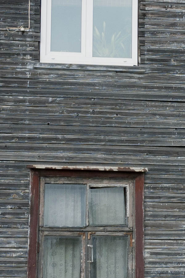 Photo 20116: Facade with worn, black board partition and brown and white windows