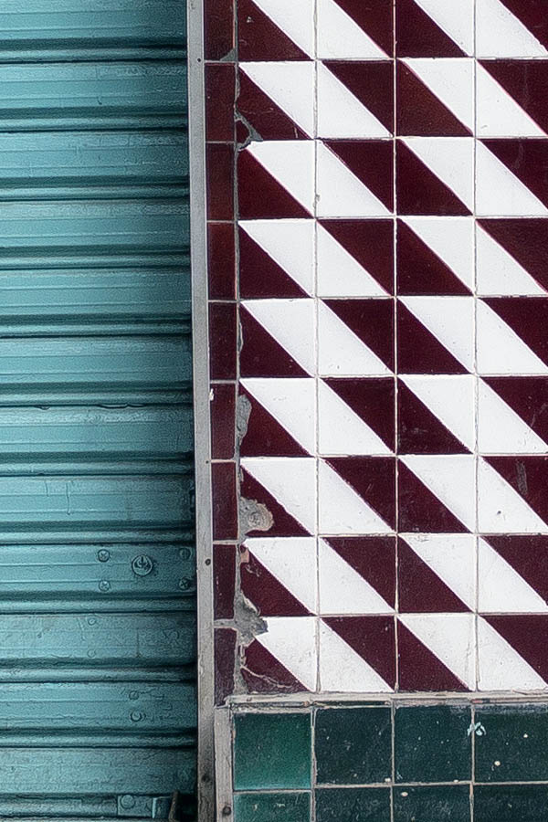 Photo 24546: Facade with brown and white tiles and two shop doors covered by turquoise security shutters