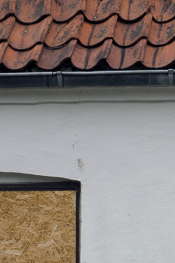 Photo 25138: Facade of worn, white house with blinded windows, ready for demolition