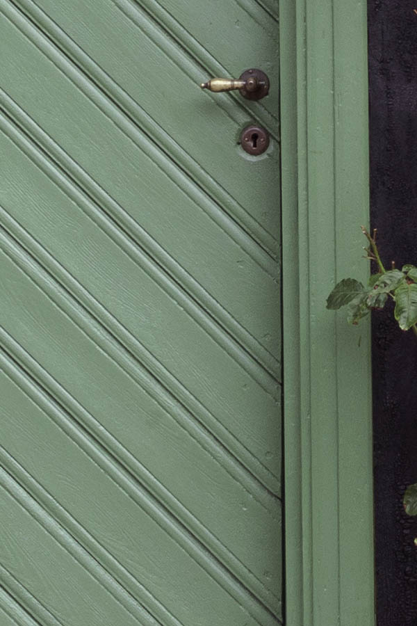 Photo 27088: Facade with green door of diagonal boards and two windows with two frames and four panes each.