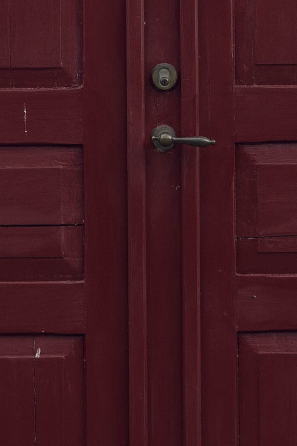 Photo 27092: Facade with panelled, red double door and two windows with two frames and six panes each.