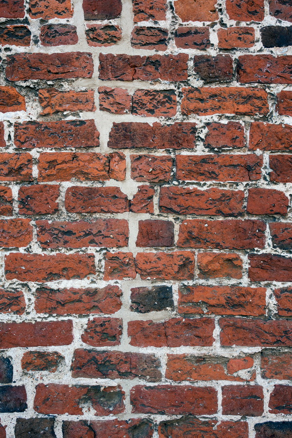 Photo 25292: Worn brick wall with red and black colours
