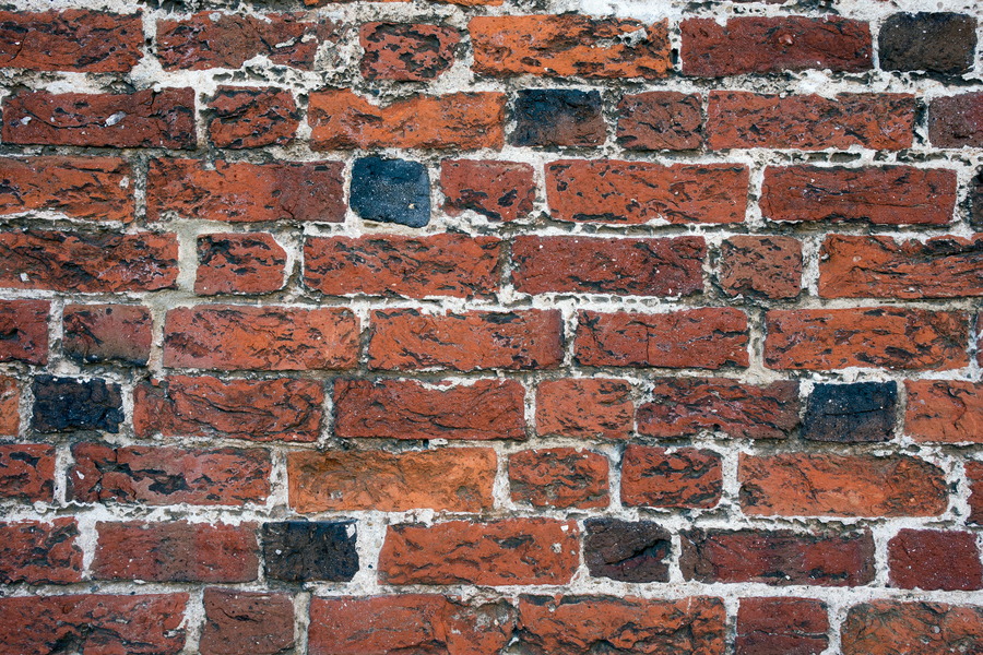 Photo 25293: Worn brick wall with red and black colours.