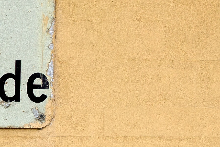 Photo 25117: Yellow, plastered brick wall with sign 