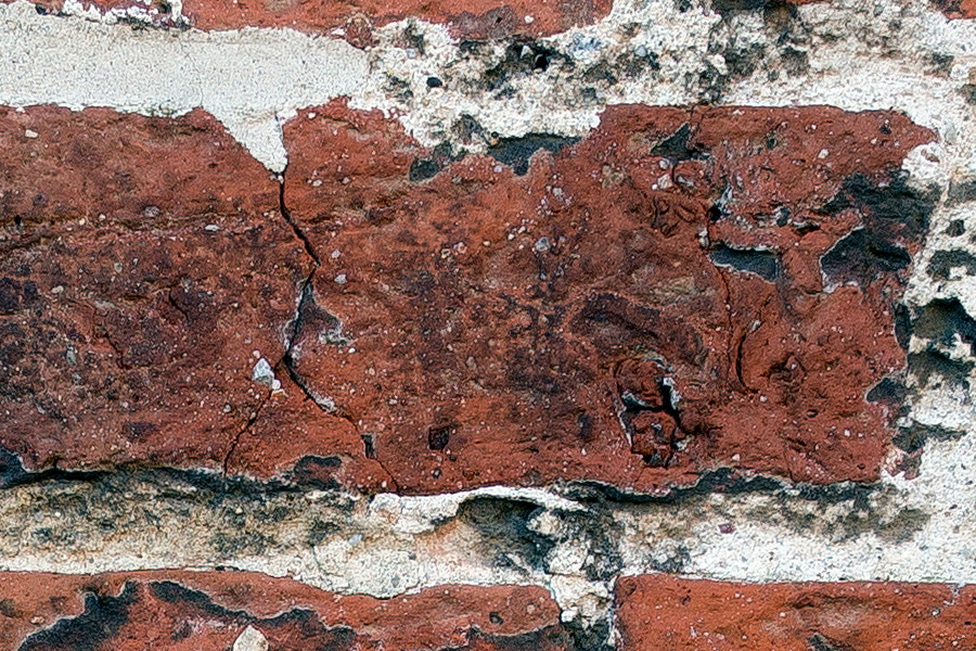 Photo 25292: Worn brick wall with red and black colours