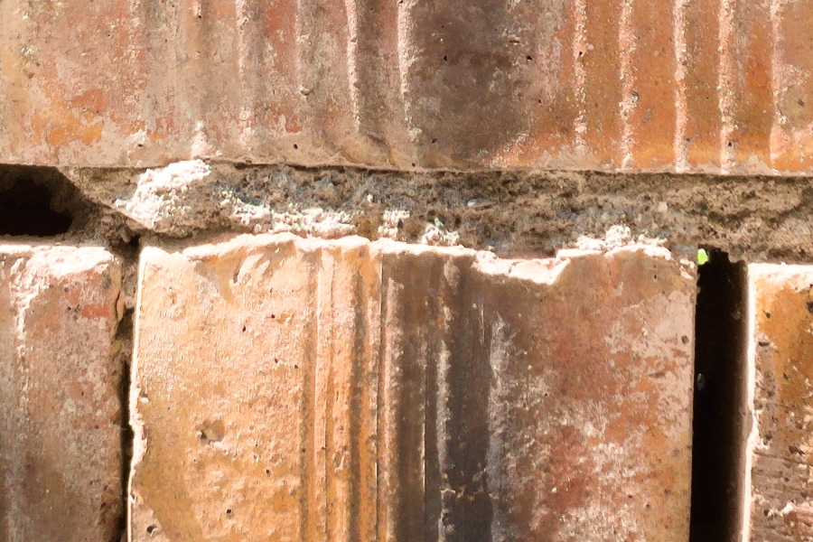 Photo 27405: Rough, orange wall of bricks with grafitti